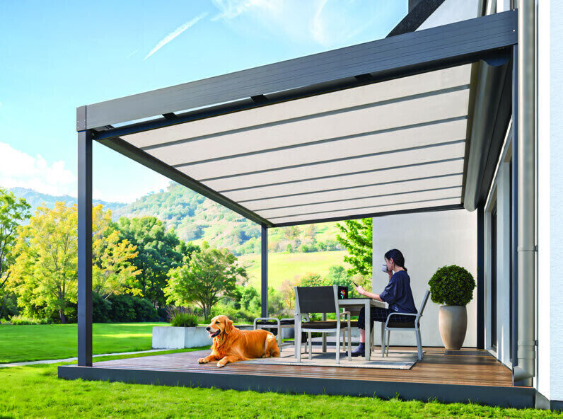 Terrassendach mit Unterdachmarkise, darunter eine Frau am Tisch und ein Hund
