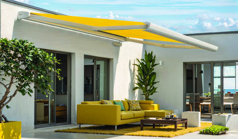 Gelbe Kassettenmarkise über einer Terrasse mit Sofa
